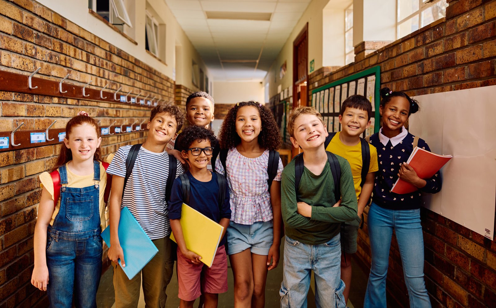 Portrait of multiethnic elementary school children smiling at camera in school corridor