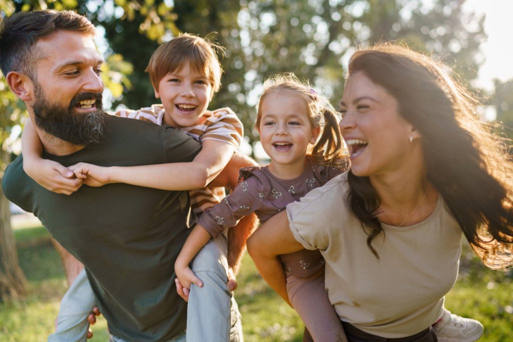 Family enjoying piggyback rides outdoors laughing and bonding
